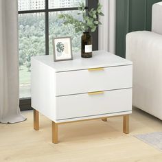 a white table with two drawers in front of a window and a plant on top