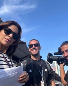 two men and a woman standing next to each other in front of a camera set