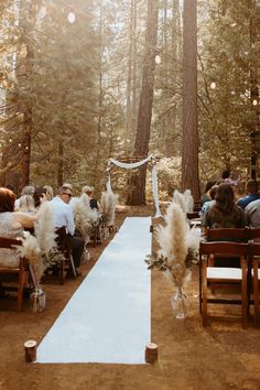 an outdoor ceremony in the woods with white aisle and pamolite flowers on it