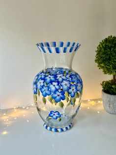 a blue and white vase sitting next to a potted plant on top of a table