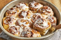 a pan filled with cinnamon rolls covered in icing