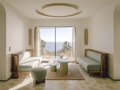 a living room filled with furniture and a large window overlooking the ocean in front of it