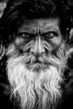 black and white photograph of an old man with long hair, beard and big eyes