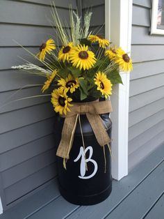 a large vase with sunflowers in it on the side of a house door