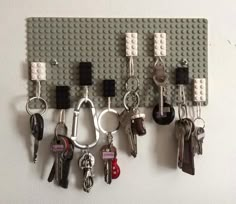 several keys hang on a peg board made out of legos and key chains, which are attached to the wall