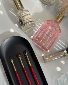 three red brushes sitting on top of a black tray next to bottles and other items