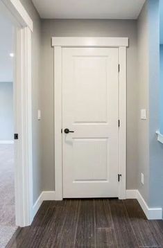 an empty room with a white door and blue walls in the corner, along with hardwood flooring