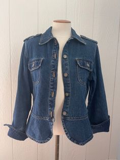 90s military style blue denim jacket. Slightly cropped and fitted. Women’s but could be unisex. Shoulder straps and front pocket detail. Rounded seams on the bottom and fold over cuffs on sleeves. 5 metal buttons down the front as well as on both shoulder straps and front pockets. Condition: Great Size: PS (small) women’s or unisex Brand: BillBlass 100% Cotton Measurements: Total length: 23 1/2” Bust: 42” Fitted Utility Denim Jacket With Pockets, Vintage Fitted Button-up Denim Top, Fitted Denim Jacket With Flap Pockets, Fitted Utility Denim Jacket In Medium Wash, Fitted Dark Wash Utility Denim Jacket, Fitted Utility Denim Jacket, Fitted Blue Denim Jacket With Flap Pockets, Fitted Long Sleeve Utility Denim Jacket, Fitted Utility Denim Jacket With Button Closure