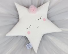 a white pillow with a pink flower on it's side and eyes drawn in the shape of a star