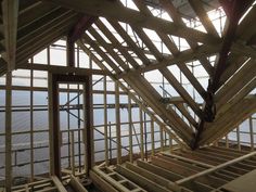 the inside of a building that is being built with wooden framing and windows on each side