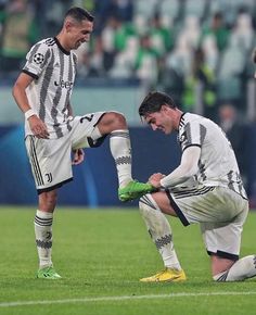 two soccer players are sitting on the field and one is holding his knee while the other sits