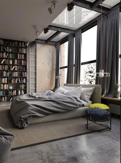 a bedroom with a bed, bookshelf and large windows in it's walls