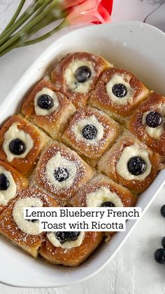 lemon blueberry french toast with ricotta in a white casserole dish next to fresh flowers