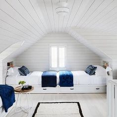 an attic bedroom with two beds and white walls