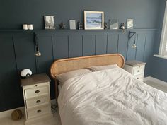 a bed sitting in a bedroom next to a white dresser and window with pictures on the wall