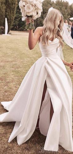 a woman in a white wedding dress holding flowers