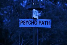 two street signs on a pole in front of some trees and blue sky behind them