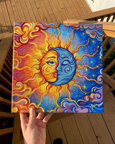 a person holding up a painting with the sun and moon on it's face