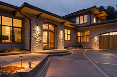 a large house with lights on in the front and side windows at night, lit up by outdoor lighting