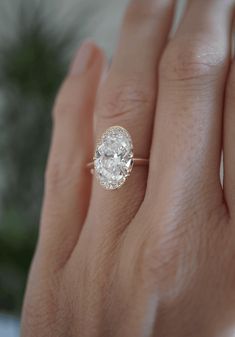 a woman's hand with a diamond ring on top of her finger and the other hand holding an engagement ring