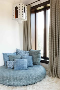 a round bed with pillows in front of a window