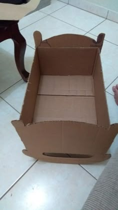 an open cardboard box sitting on the floor next to a person's hand and foot