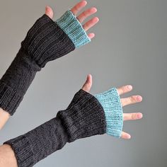 two hands with knitted mittens on top of each other, one wearing a blue and gray sweater