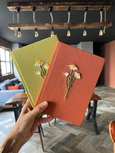 someone holding up two books with flowers on them