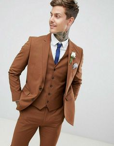 a man in a brown suit with a tattoo on his neck and chest is posing for the camera