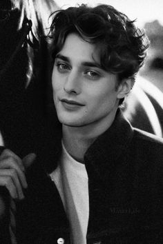 black and white photograph of a young man with curly hair wearing a jacket looking at the camera