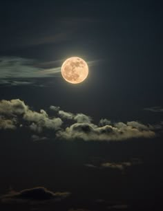 the full moon is shining brightly in the dark night sky with fluffy clouds around it