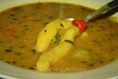 a spoonful of soup is being held by someone's hand over the bowl