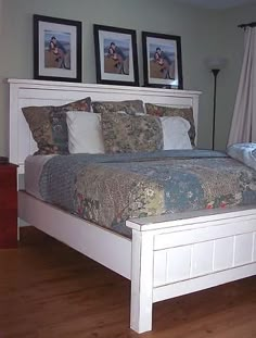 a bed with two pictures on the wall above it and a night stand next to it