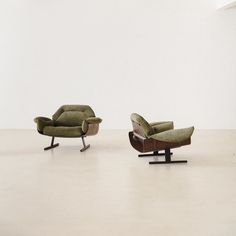 two green chairs sitting next to each other on top of a white floor in an empty room