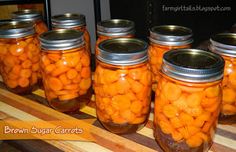 several jars filled with carrots sitting on top of a wooden table next to each other