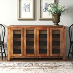 a wooden cabinet sitting next to two chairs and a potted plant on top of it