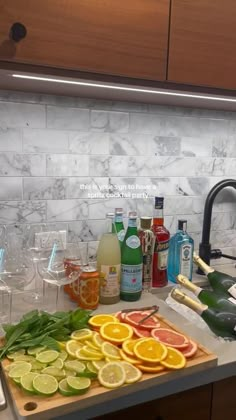 the kitchen counter is covered with many different types of drinks and fruit, including oranges