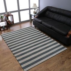 a black leather couch sitting on top of a hard wood floor next to a window