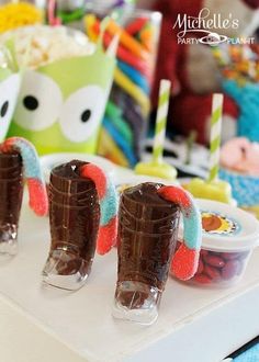 three chocolate candy boots sitting on top of a white table next to other treats and candies