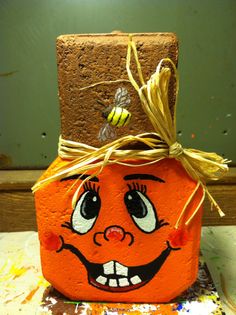 an orange pumpkin with a face painted on it's side and a bee sitting on top of it