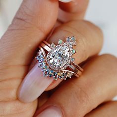 a woman's hand holding a ring with an oval shaped diamond in the center