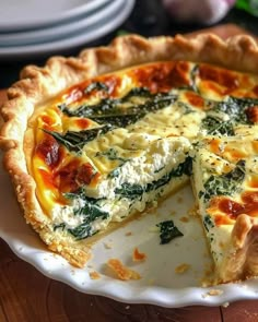 a quiche with cheese and spinach is on a white plate, ready to be eaten