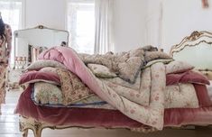 a woman standing next to a bed covered in blankets