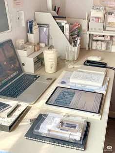 a laptop computer sitting on top of a desk next to books and other office supplies