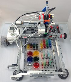 a lego robot is sitting on top of a table filled with paint and other items