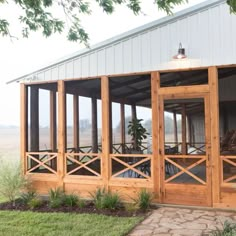 a screened porch in front of a white building with wooden railings and glass doors