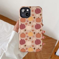 a person holding up a phone case with pumpkins and acorns on it