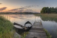 a boat sitting on top of a wooden dock next to a body of water at sunset