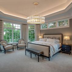 a bedroom with a large bed and chandelier in the corner, along with two chairs