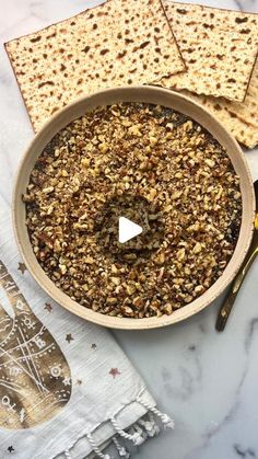 a bowl filled with granola next to crackers on top of a white table